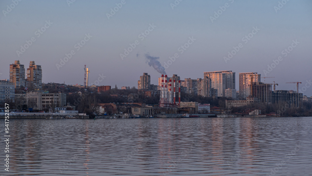 View of the city from the water. Smoke comes from chimneys.