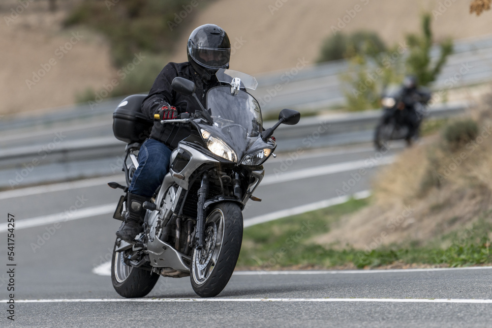 Motorcyclist riding on a curvy road with a large-displacement motorcycle. Motorcyclist riding on a curvy road with a large-displacement motorcycle.