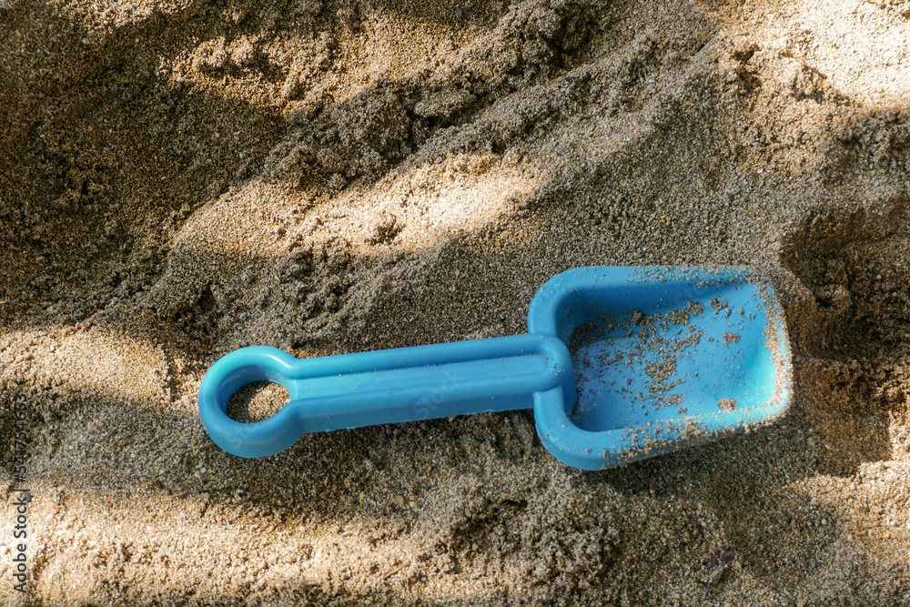 Plastic shovel on the white sand of the beach. Illustration for kids activities on the beach Plastic shovel on the white sand of the beach. Illustration for kids activities on the beach