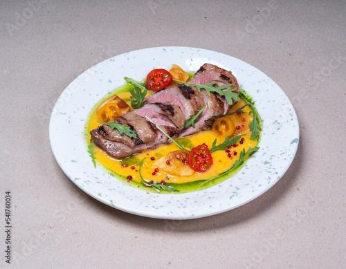 Grilled meat with delicious yellow sauce. Cherry tomatoes. Beautiful plate. Fresh tasty food in restaurant.