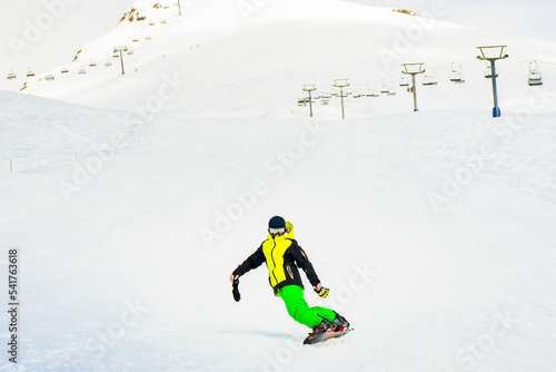 Gudauri, Georgia - 25th february, 2022: caucasian boy snowboard on slope front view stylish alone with no helmet and gloves in cold winter conditions in ski resort