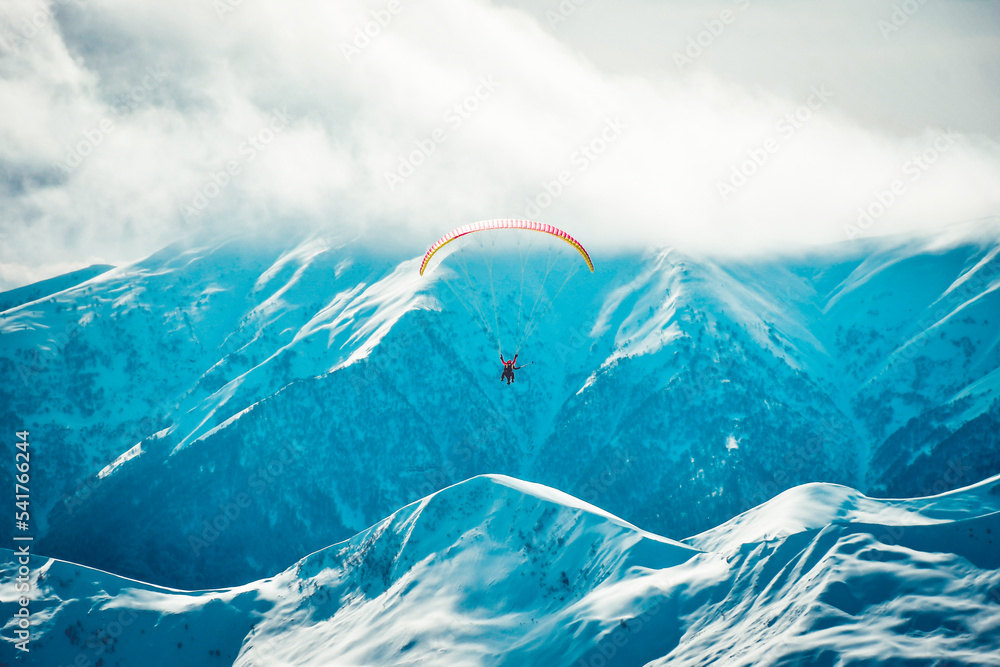 Gudauri ski resort panorama with tandem paragliders high in air in cold winter day with caucasus background