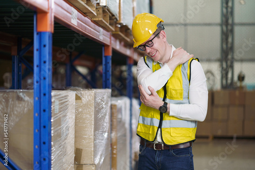 Back ache concept of factory worker. Young man looking painful expression. Portrait of young male feeling pain while touching shoulder and his back by hand. Man suffering from office syndrome.