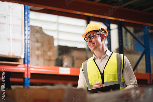 Portrait of Caucasian young man inspector working in warehouse storage with laptop.