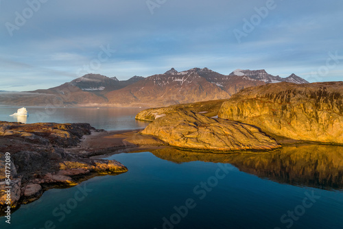 Aerial view of the coastline with iceberg and mountain in background, Sermersooq, Greenland.