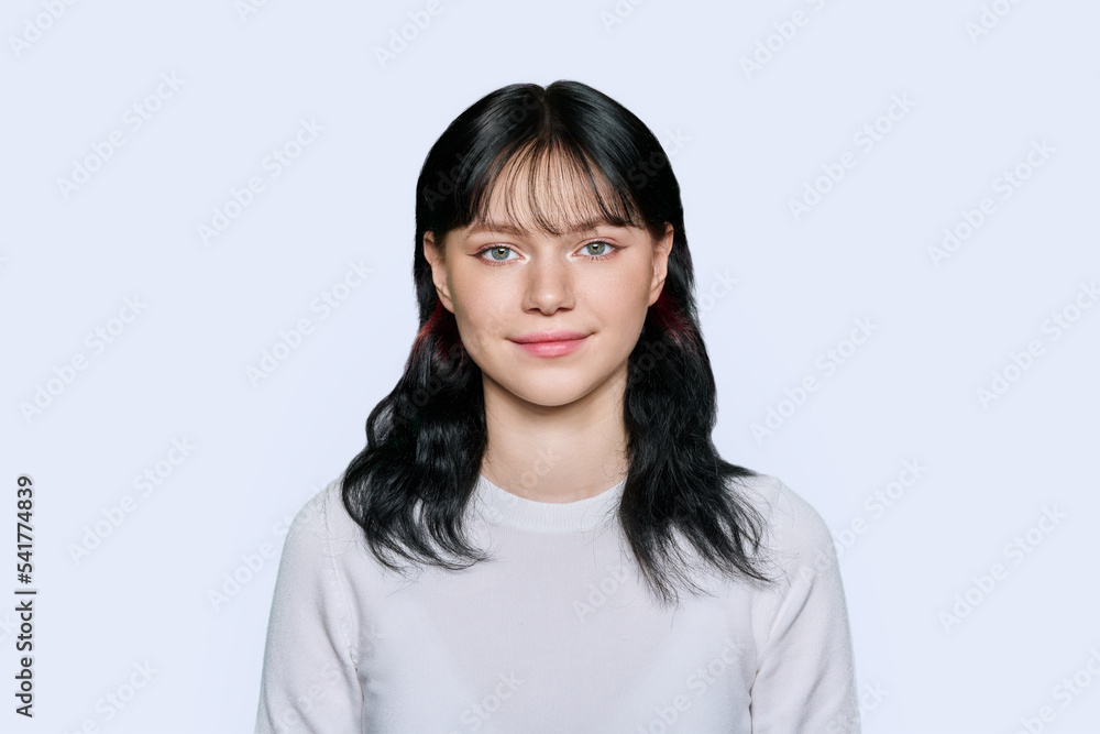 Smiling young female looking at camera on light background Smiling young female looking at camera on light background