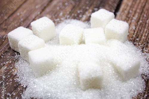 Sugar cubes and crumbs. White sugar on a wooden table.