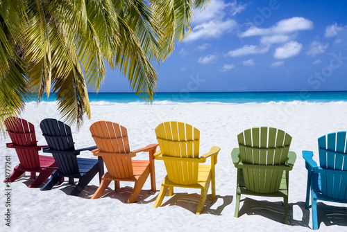 Colored wooden chairs on white sand beach photo