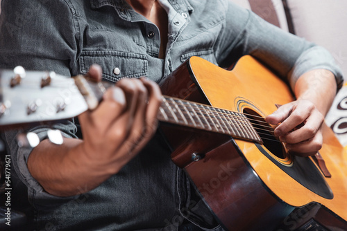 Hombre en casa con guitarra acústica, tocando y cantando. Concepto de músico compositor. guitarrista 