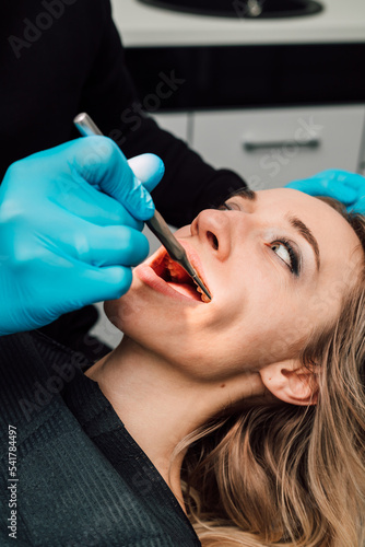 A woman lies in a dentist's chair for an examination. Examination of oral cavity