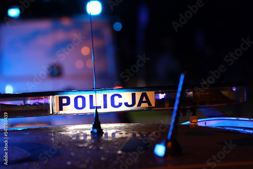 Akcja nocna  alarmowa policji - Sygnalizator błyskowy niebieski na dachu radiowozu policji polskiej w nocy. Światła policyjne.