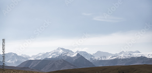 Panorama of mountain hills and peaks with snow and glaciers on an autumn day in the Caucasus  an unusual cloudy blue sky over the mountains