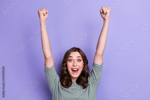 Photo of excited funny girl fists up celebrating big season sale clothing low prices shopping mall hooray yeah isolated on purple color background