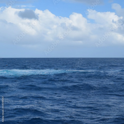 Deep blue wavy ocean on a sunny day with clouds in the sky
