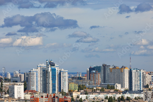 The modern architecture of new buildings rises above the roofs of old buildings in the urban landscape. © Sergii
