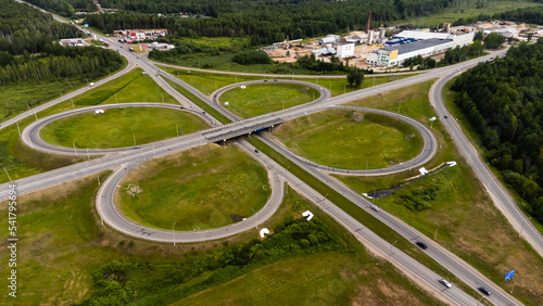 Aerial view of highway in city. Cars crossing interchange overpass. Highway interchange with traffic. Aerial bird's eye photo of highway. Expressway. Road junctions. Car passing. Top view from above. © Павел Шульмин