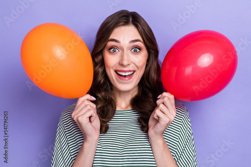 Close up photo of astonished positive lady wear stylish clothes two hand hold balloon rejoice party isolated on purple color background © deagreez