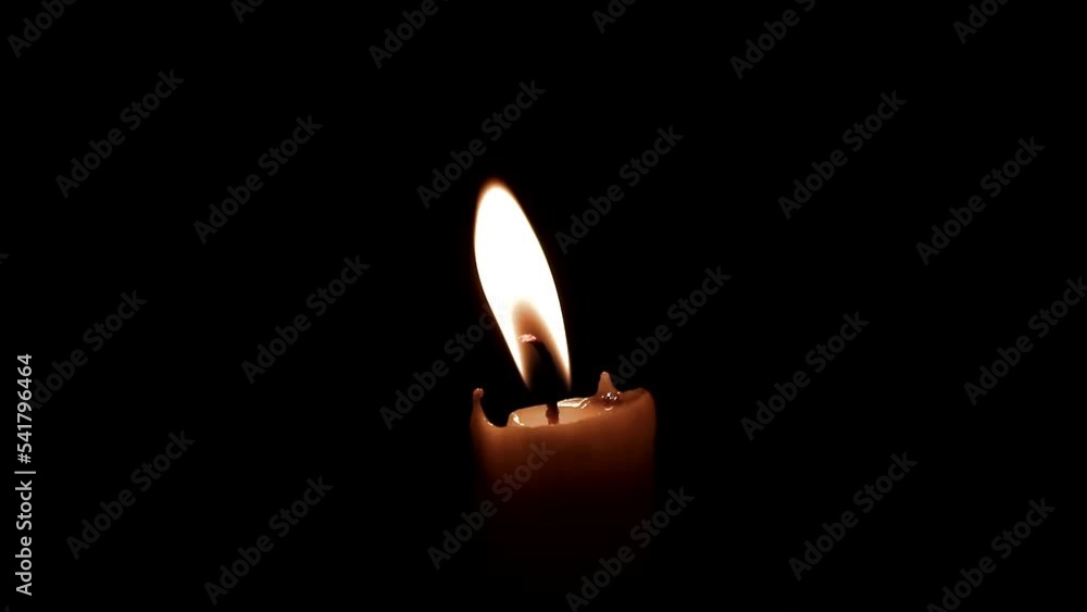 Burning candle. The candle burns in the dark. Candle flame on a black background Burning candle. The candle burns in the dark. Candle flame on a black background