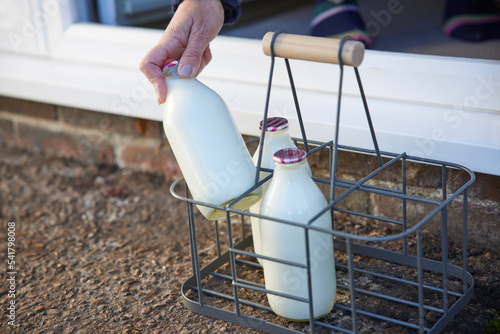 Photos Person Picking Up Bottle Of Milk From House Door Step
