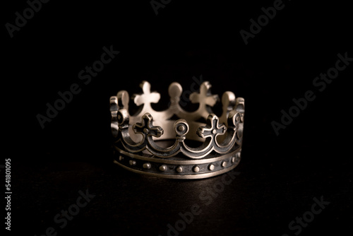 crown shaped ring made of solid sterling silver with cross on it. jewelry for brutal men on black background  photo