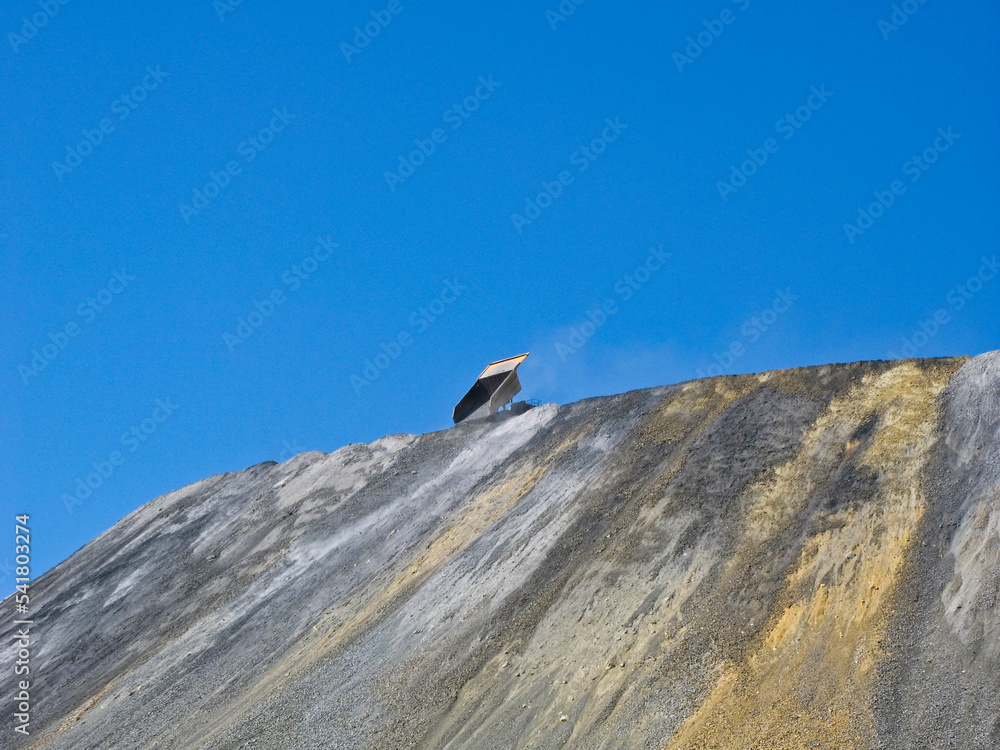 A single dump truck dumps rock on a huge pile A single dump truck dumps rock on a huge pile