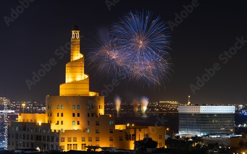 Beautiful shot of the illuminated Fanar Mosque in Qatar with fireworks in the night sky photo