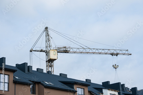 A house with a black roof, a construction crane in the background. Housing construction