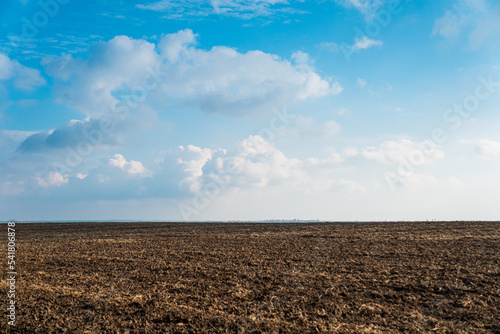 A plowed field on the background of a blue sky with clouds
