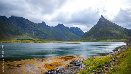panorama of the landscape of the lofoten islands, norway, small colourful houses on the seashore under huge rocks and cliffs, paradise beaches in rocky fjords