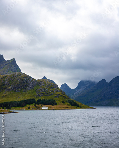 panorama of the landscape of the lofoten islands, norway, small colourful houses on the seashore under huge rocks and cliffs, paradise beaches in rocky fjords