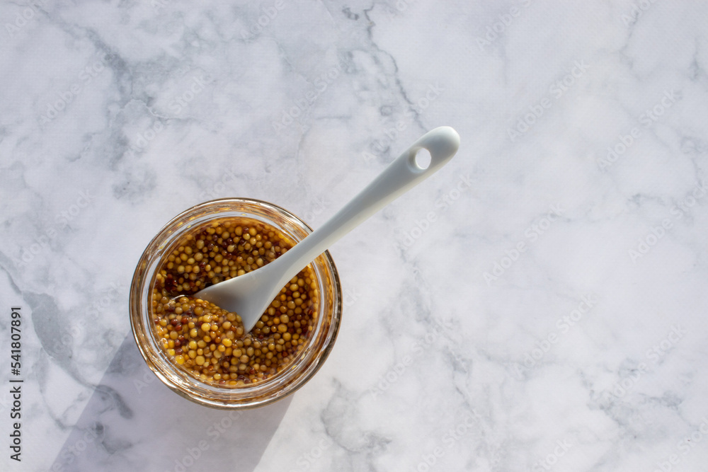 Mustard seeds sauce in glass jar on marble table background. Top view, copy space Mustard seeds sauce in glass jar on marble table background. Top view, copy space