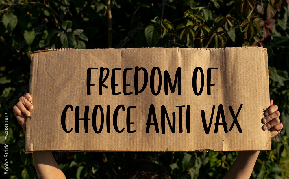A poster with the words FREEDOM OF CHOICE ANTI VAX in the hands of a