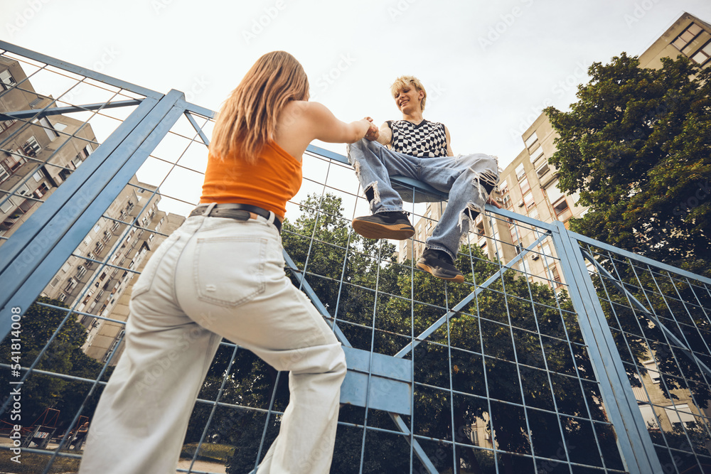 A rebellious teenagers climbing the fence on a street.