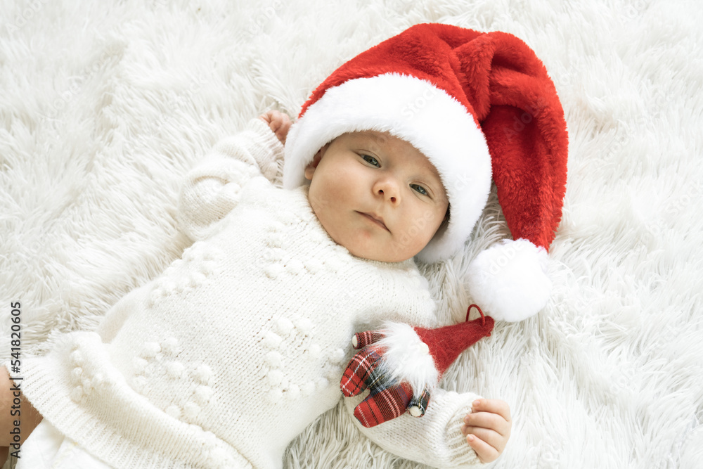 Christmas portrait of cute little newborn baby girl, wearing santa hat and hugging little cute snowman toy, winter time Christmas portrait of cute little newborn baby girl, wearing santa hat and hugging little cute snowman toy, winter time