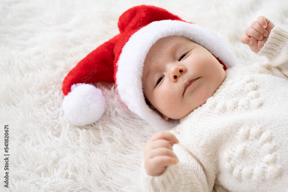 Close up Christmas portrait of cute little newborn baby girl, wearing santa hat and hugging little cute snowman toy, winter time Close up Christmas portrait of cute little newborn baby girl, wearing santa hat and hugging little cute snowman toy, winter time