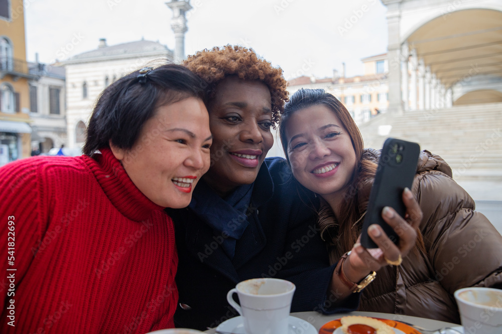 Obraz premium Smiling friends having fun sharing something on the mobile phone. Diversity concept