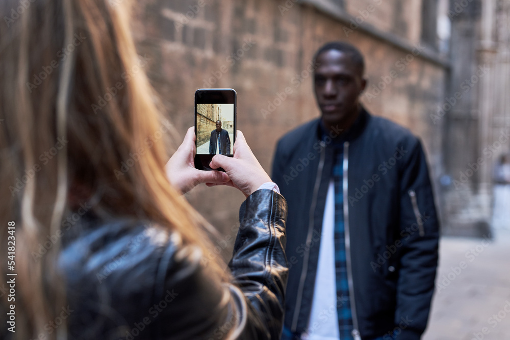 Fototapeta premium Girlfriend making photograph of her boyfriend in the street.