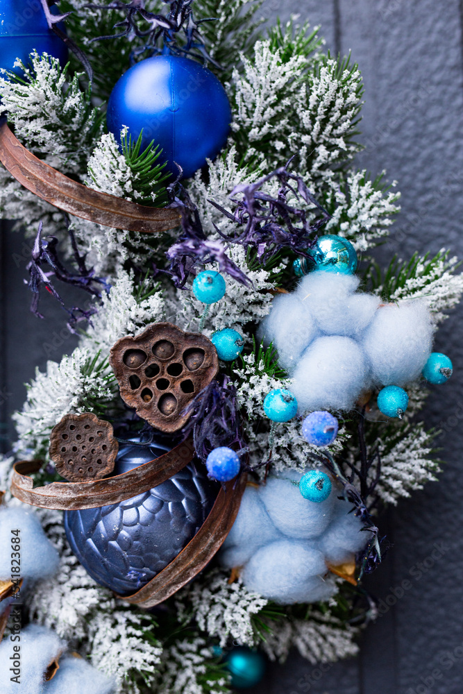 Christmas wreath with nobilis fir and cotton and blue balls on grey wooden background. Christmas decor