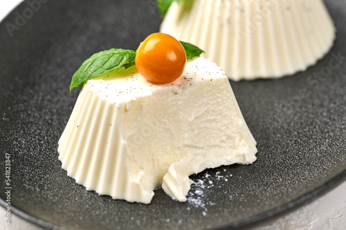 Macro uncut homemade panna cotta with natural vanilla pod, physalis or winter cherry and mint, selective focus