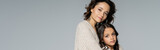 brunette woman and girl in knitwear looking at camera isolated on grey, banner