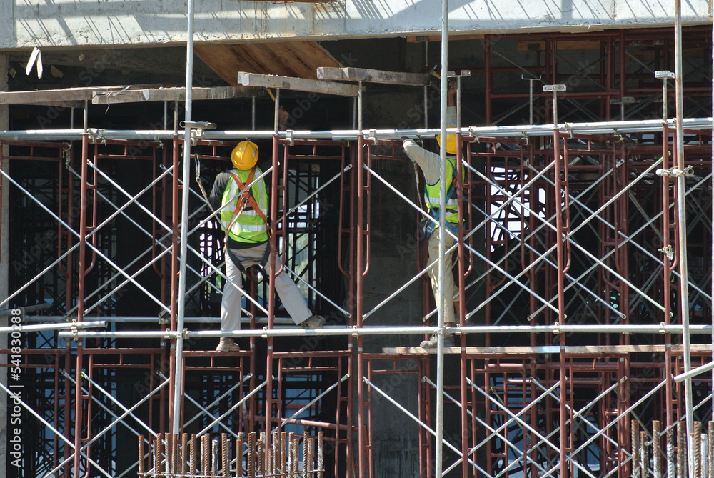 Fototapeta premium PERAK, MALAYSIA -APRIL 05, 2016: Construction workers wearing safety harness and installing scaffolding at high level in the construction site.