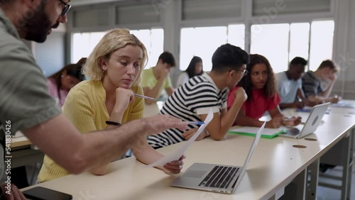 Male teacher helping high school student female doing exercises in classroom - Education and college people concept