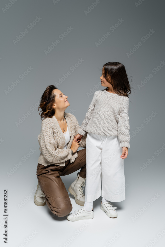 happy woman holding hand of stylish daughter on grey background happy woman holding hand of stylish daughter on grey background