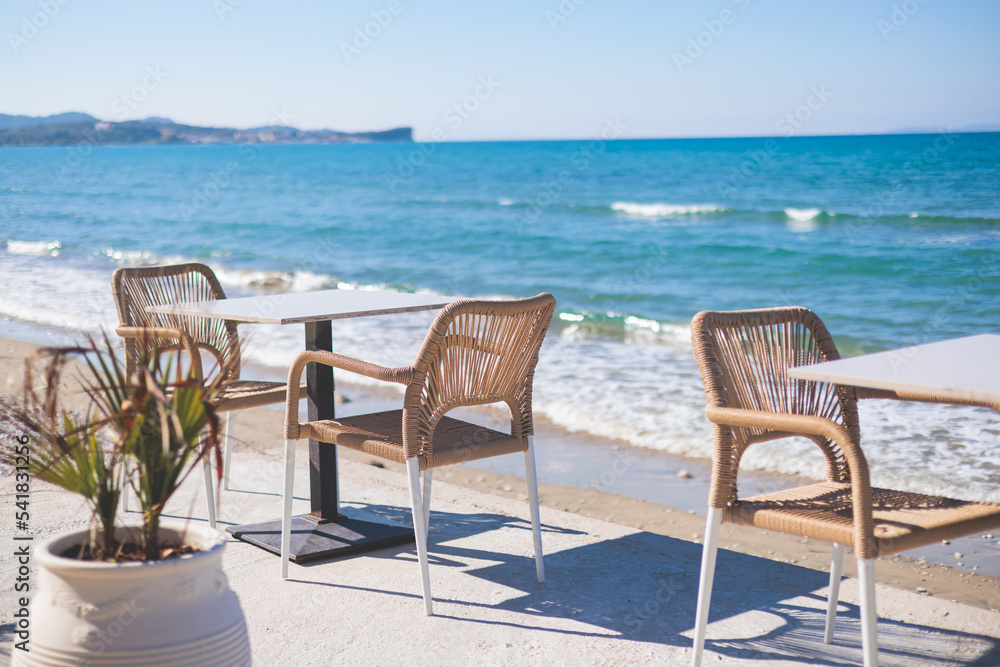 Restaurant terrace by the sea, seaside view cafe on the beach, empty chairs and tables Ionian sea shore, Greece, blue sea with crystal clear water Restaurant terrace by the sea, seaside view cafe on the beach, empty chairs and tables Ionian sea shore, Greece, blue sea with crystal clear water
