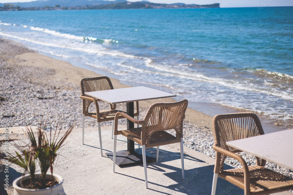 Restaurant terrace by the sea, seaside view cafe on the beach, empty chairs and tables Ionian sea shore, Greece, blue sea with crystal clear water Restaurant terrace by the sea, seaside view cafe on the beach, empty chairs and tables Ionian sea shore, Greece, blue sea with crystal clear water