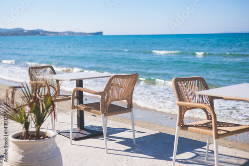 Restaurant terrace by the sea, seaside view cafe on the beach, empty chairs and tables Ionian sea shore, Greece, blue sea with crystal clear water © tsuguliev