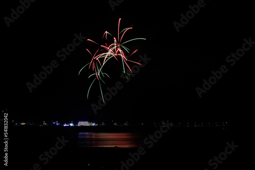 A scenic view of a majestic multicolor firework with reflection over the water under a majestic black sky photo