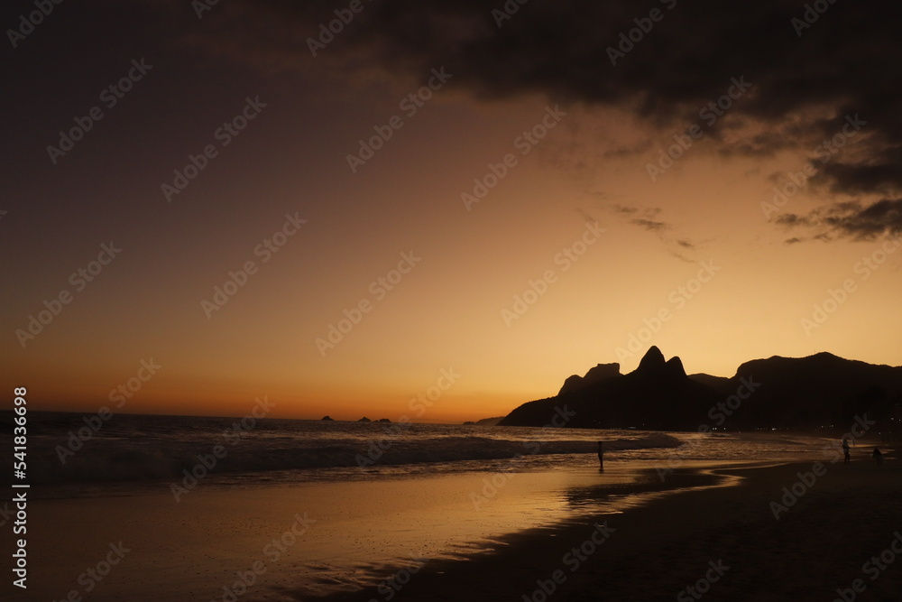 Rio de Janeiro, RJ, Brazil, 2022 - People walking in silhouette at Ipanema Beach at sunset