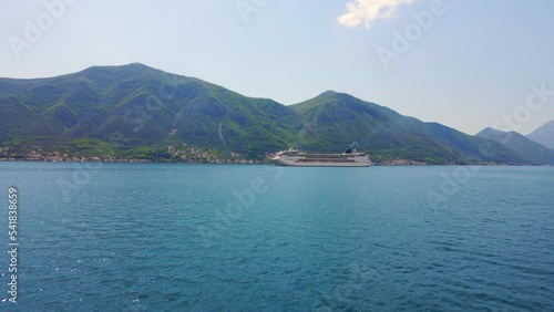 Aerial video. A big cruize ship is moving through the Boka Kotor Bay. Summer in Montenegro. Slowmotion shot photo