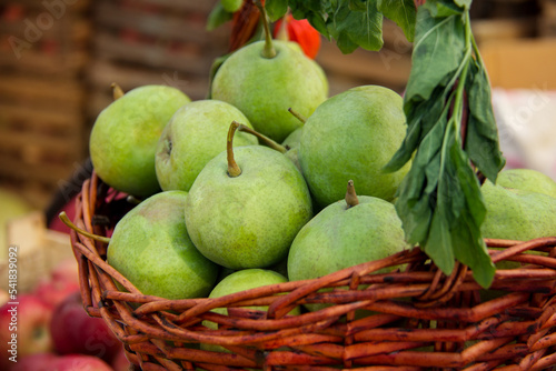 Round green ripe pears in a wicker wooden basket